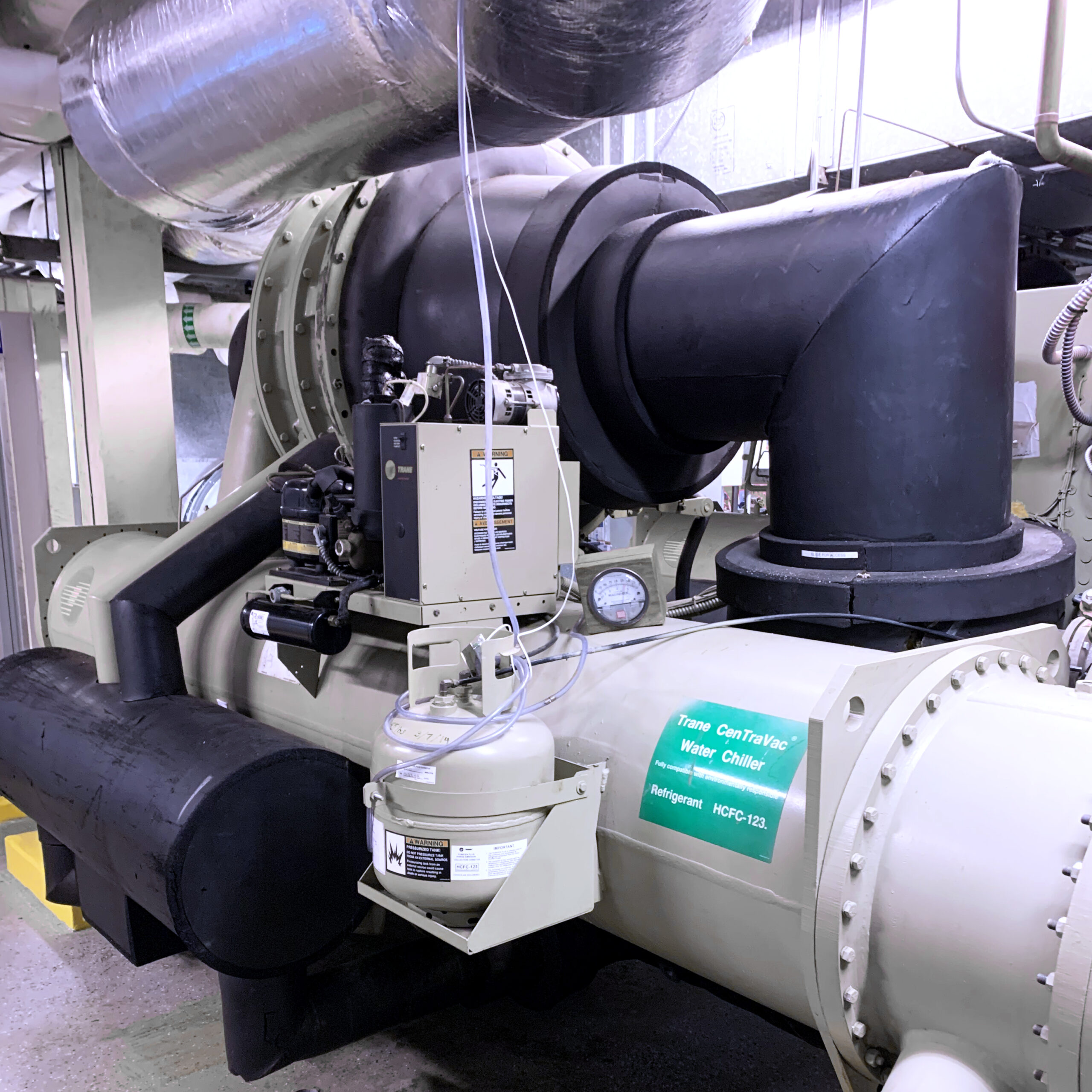 Trane CenTraVac water chiller system with connected piping and a refrigerant container in a facility