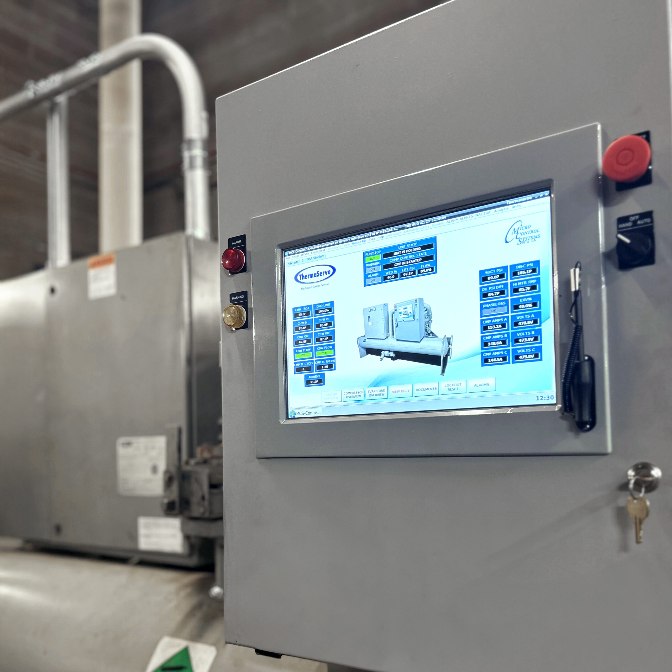 Close-up of a control panel with a digital display showing chiller system data and the ThermaServe logo