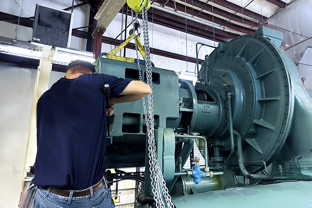 Technician servicing a large industrial chiller inside a mechanical room.